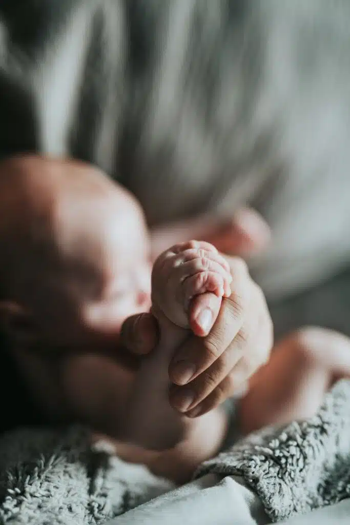 Mano de un adulto sostiene la mano diminuta de un bebé recién nacido