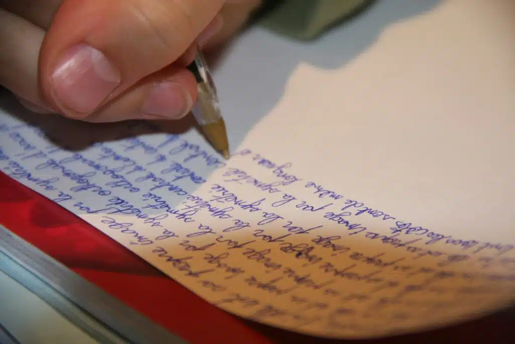 Mano escribiendo una carta de amor con bolígrafo, idea para acompañar un regalo de aniversario