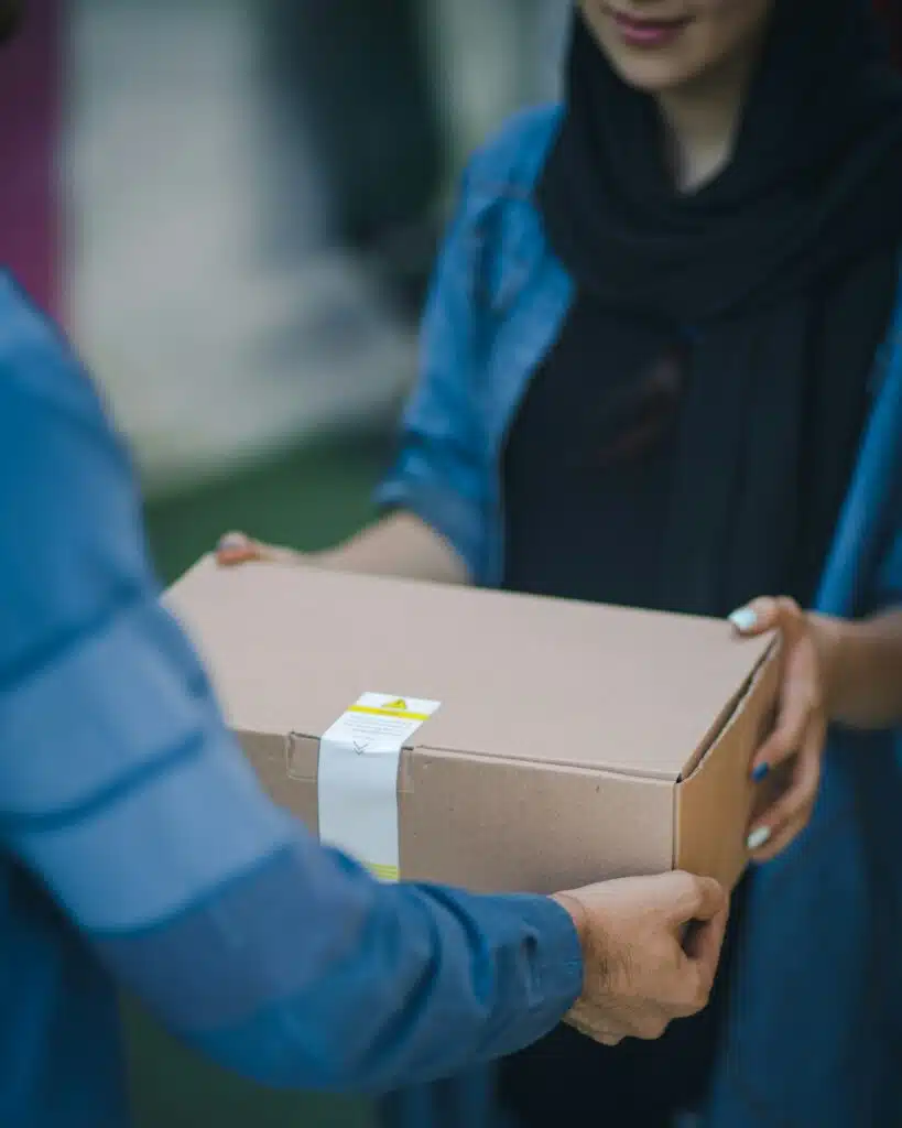 Mensajero entrega una caja de regalo en manos de la persona que lo recibe